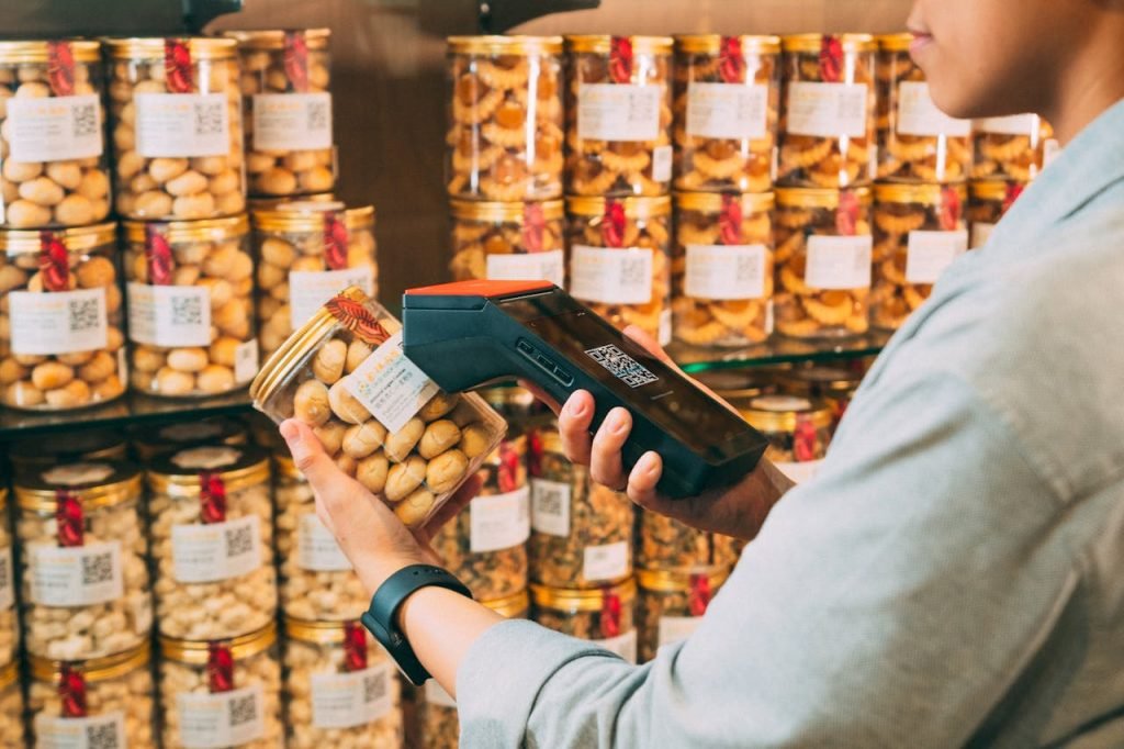 Pda Personal Digital Assistant Assistant numérique personnel Individual scanning QR codes on jars in a store with a handheld device.
